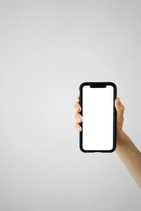 Vertical shot of a hand holding a smartphone with a blank screen, ideal for mockups.